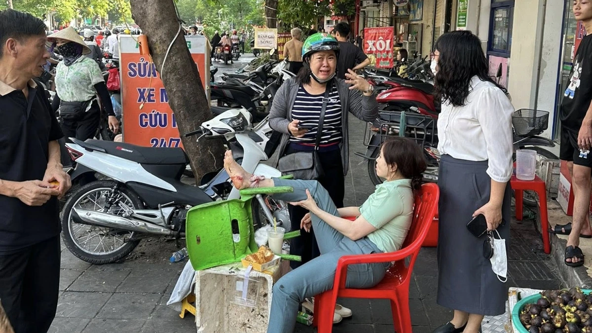 Một nạn nhân bị thương được người dân hỗ trợ sơ cứu trên vỉa hè.