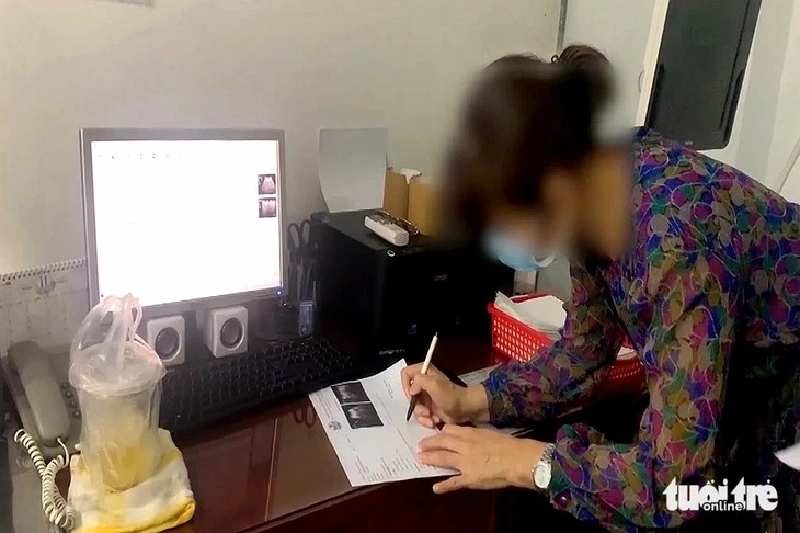 Bác sĩ người Việt in và ký trả kết quả siêu âm cho người bệnh trong một phòng khám tư có yếu tố nước ngoài. Thời điểm Thanh tra Sở Y tế kiểm tra tháng 11/2022, bác sĩ này không mặc trang phục nhân viên y tế và không đeo bảng tên. Ảnh: V.E.