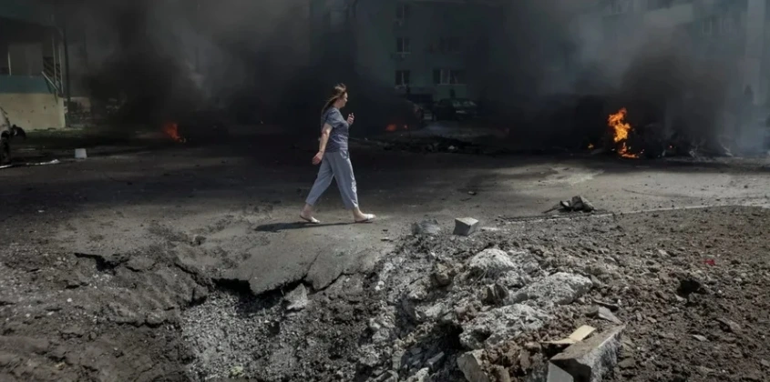 Người phụ nữ đi qua hố bom tại Kharkov. Ảnh: New Voice of Ukraine