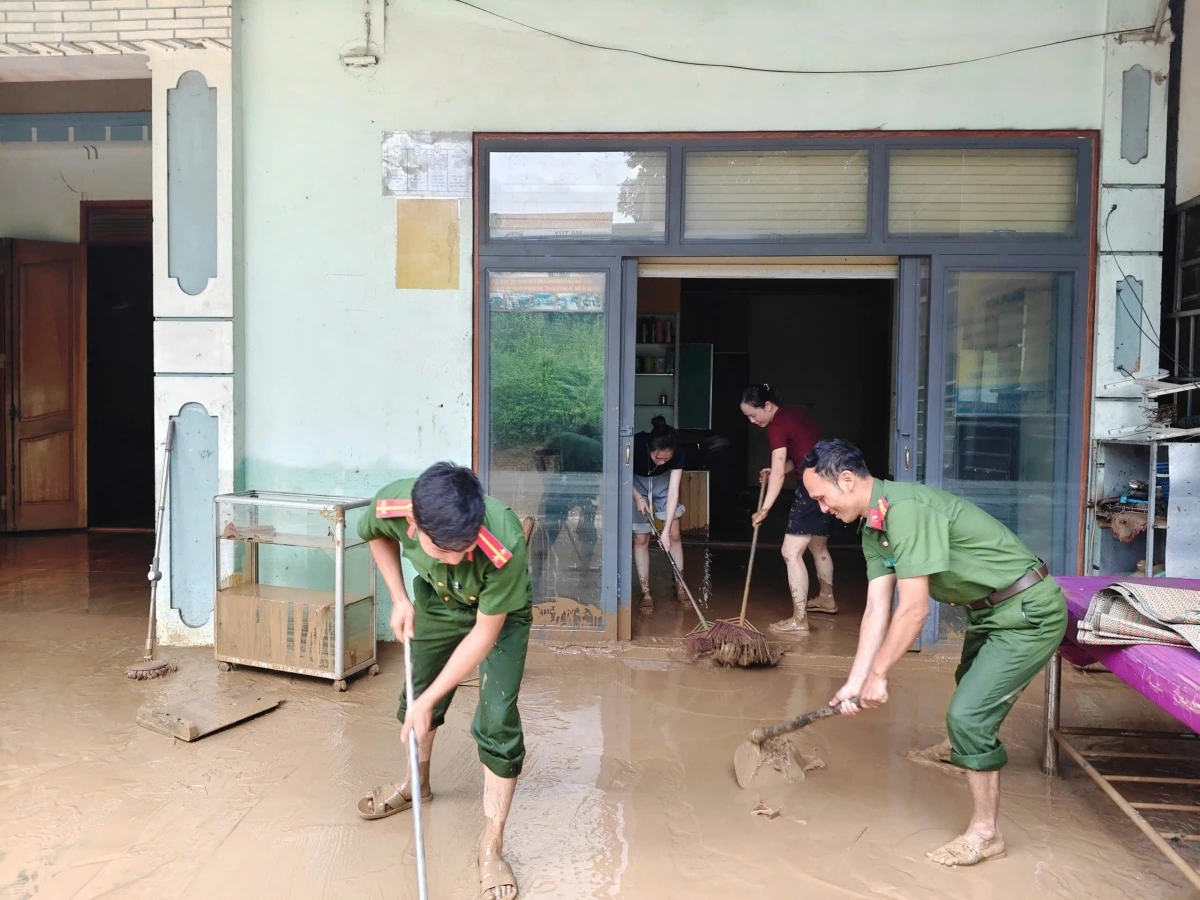 Công an xã Chiêu Lưu hỗ trợ người dân dọn dẹp nhà ở sau lũ lụt.