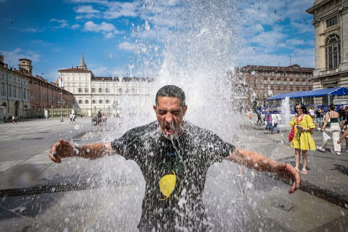 Một người đàn ông đang giải nhiệt tại đài phun nước ở Turin, Italy. Ảnh: EPA