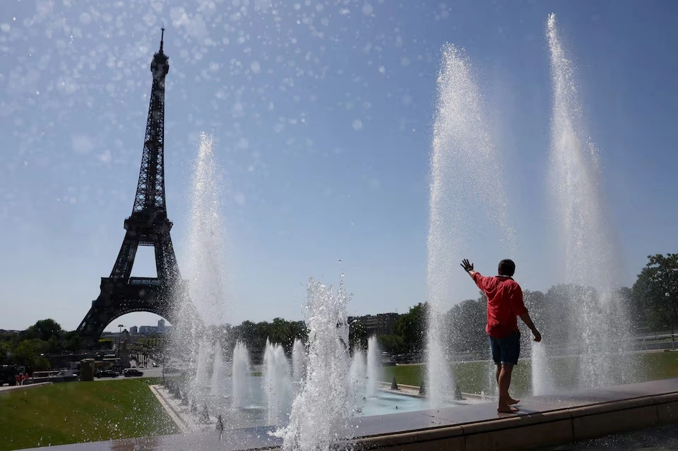 Một du khách giải nhiệt tại đài phun nước Trocadero bên cạnh tháp Eiffel khi đợt nắng nóng đầu hè tràn qua Paris, Pháp, ngày 1/7/2025. Ảnh: Reuters