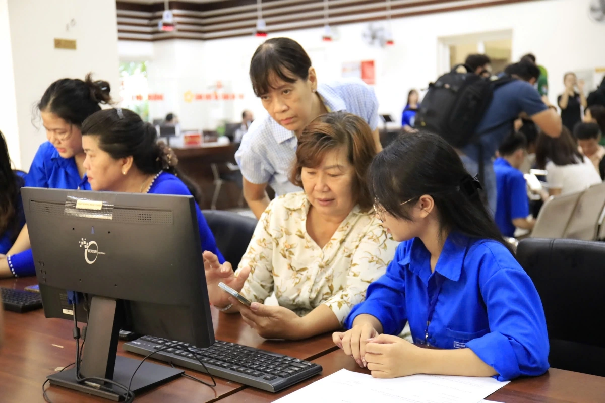 Bà Tuyết Thu được các bạn thanh niên tình nguyện hỗ trợ việc sử dụng ứng dụng VNeID (ảnh: N.M)