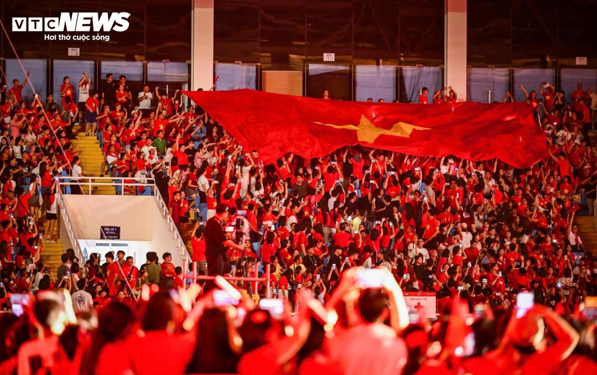 All 50,000 attendees at the stadium solemnly rise to their feet and join their voices in unison.