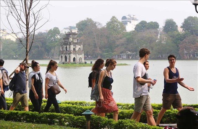 Foreign tourists walk by Hoan Kiem Lake in the centre of Hanoi. VNA/VNS Photo Thanh Dat