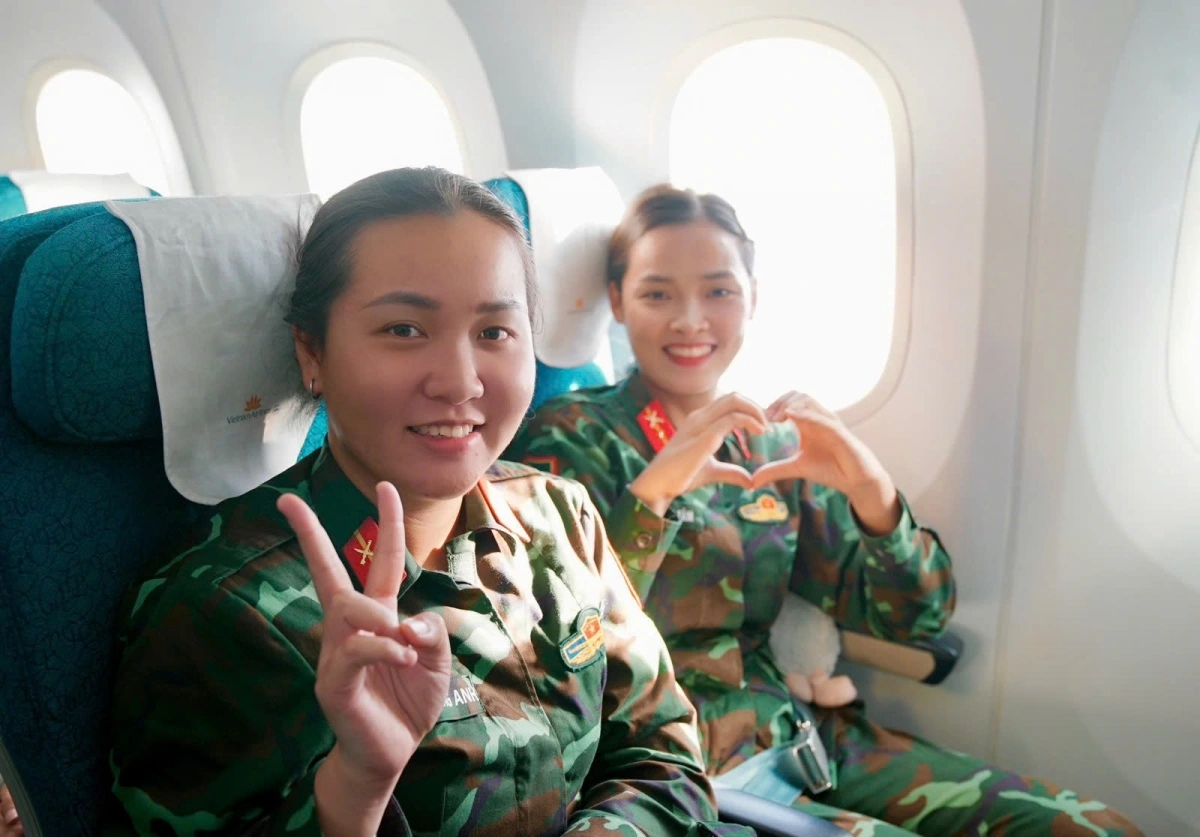 Trên chuyến bay, các tiếp viên của Vietnam Airlines cài huy hiệu cờ đỏ sao vàng trên ngực áo, mang theo sắc màu Tổ quốc trong không gian khoang bay. Hình ảnh ấy hòa chung vào không khí trang trọng của hành trình, như một lời cảm ơn gửi đến các chiến sĩ đã hoàn thành xuất sắc nhiệm vụ và trở về trong niềm tự hào.