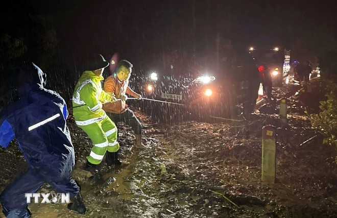 Traffic Police support people and vehicles passing through a landslide section on National Highway 7A in central province of Nghe An.