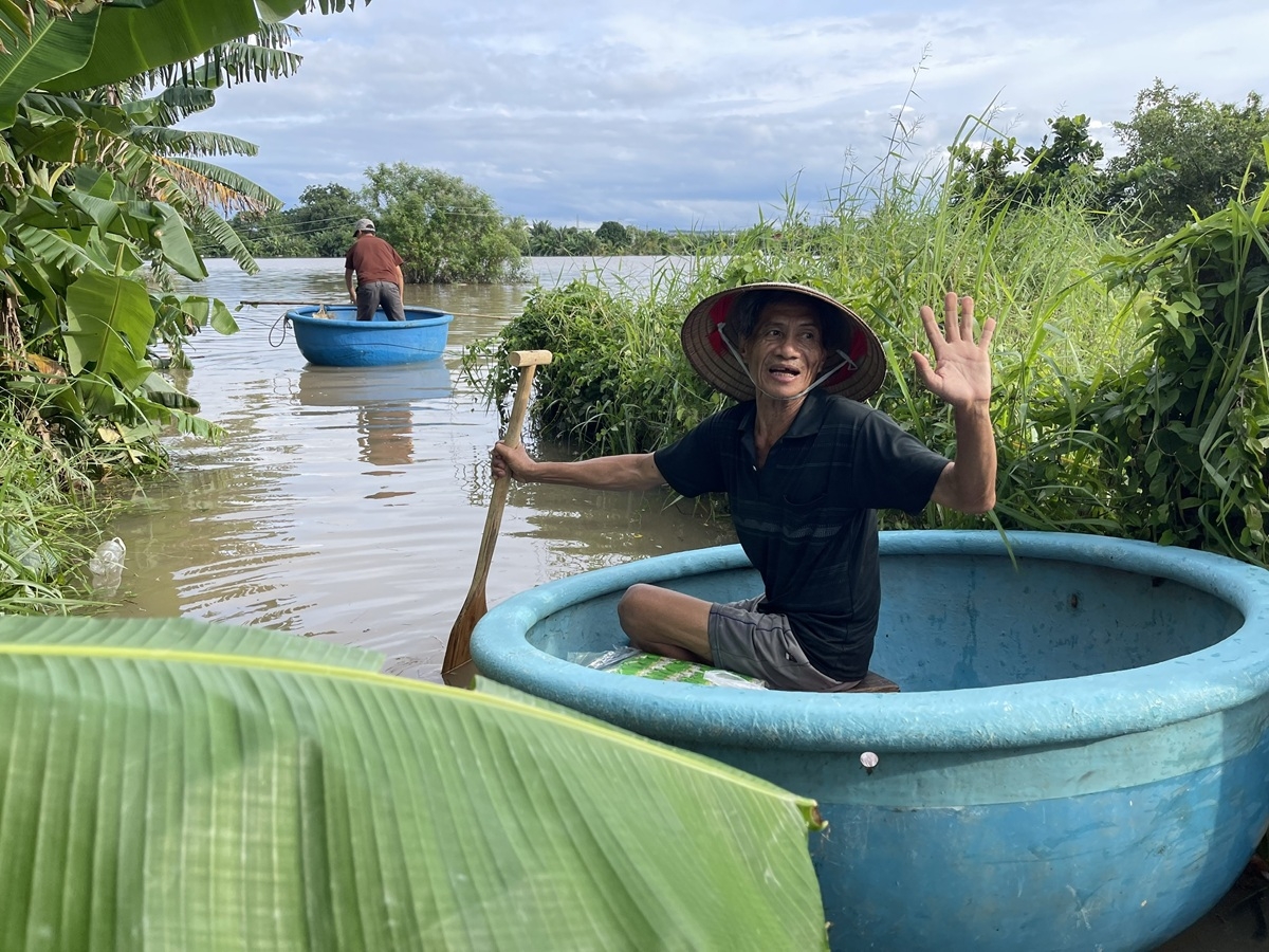 Người dân ở khu vực bị cô lập dùng thuyền thúng bơi ra nhận hàng cứu trợ. Ảnh: B.H