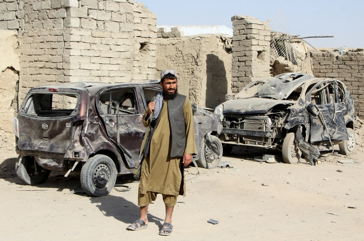 Một tay súng của Taliban đứng cạnh một chiếc ô tô bị phá hủy do cuộc không kích của quân đội Pakistan nhằm vào thị trấn Spin Boldak, tỉnh Kandahar, Afghanistan ngày 16/10. (Ảnh: Reuters)