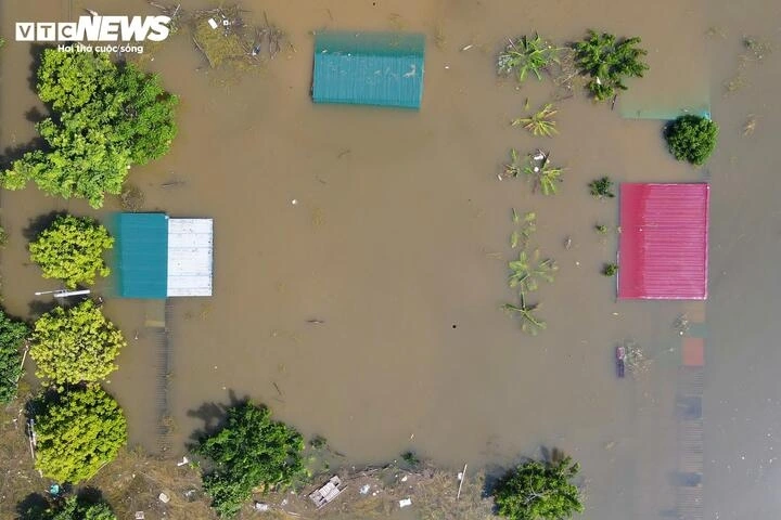 Đường xá biến mất dưới lớp nước đục ngầu, chỉ còn lác đác vài mái nhà lộ ra giữa không gian trắng xóa.