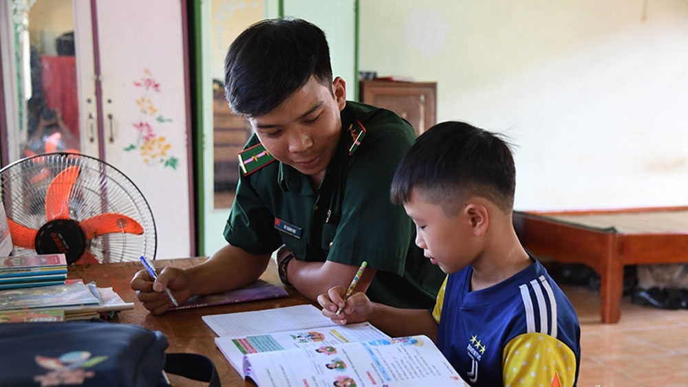 Chiến sĩ bộ đội biên phòng dạy học cho con nuôi của đồn (ảnh: QĐ) 