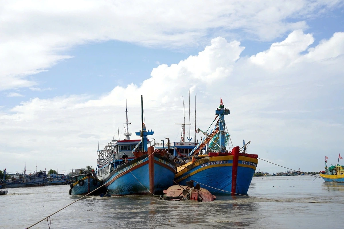 Lực lượng chức năng dùng tàu lớn để giữ không cho nước cuốn trôi tàu cá chìm. Ảnh: B.H