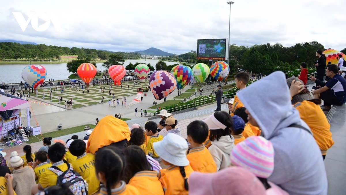 Many locals and tourists excitedly watch hot air balloons flying over the Da Lat sky, creating a vibrant festive atmosphere.