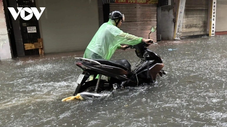 Local residents struggle to push their vehicles through deeply flooded areas.