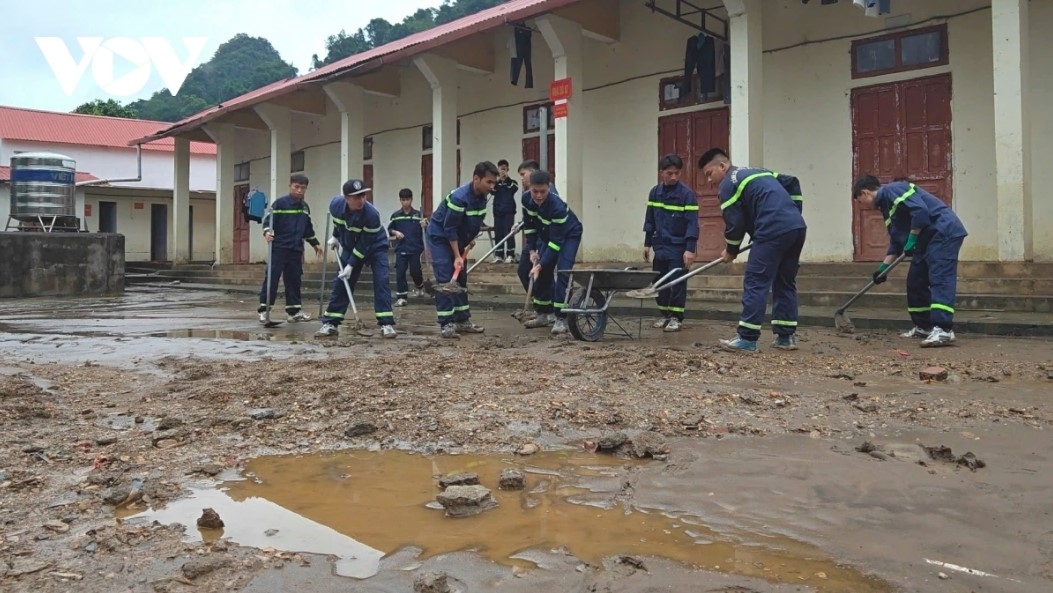 Police help residents collect trash and clean up the environment after floodwaters recede
