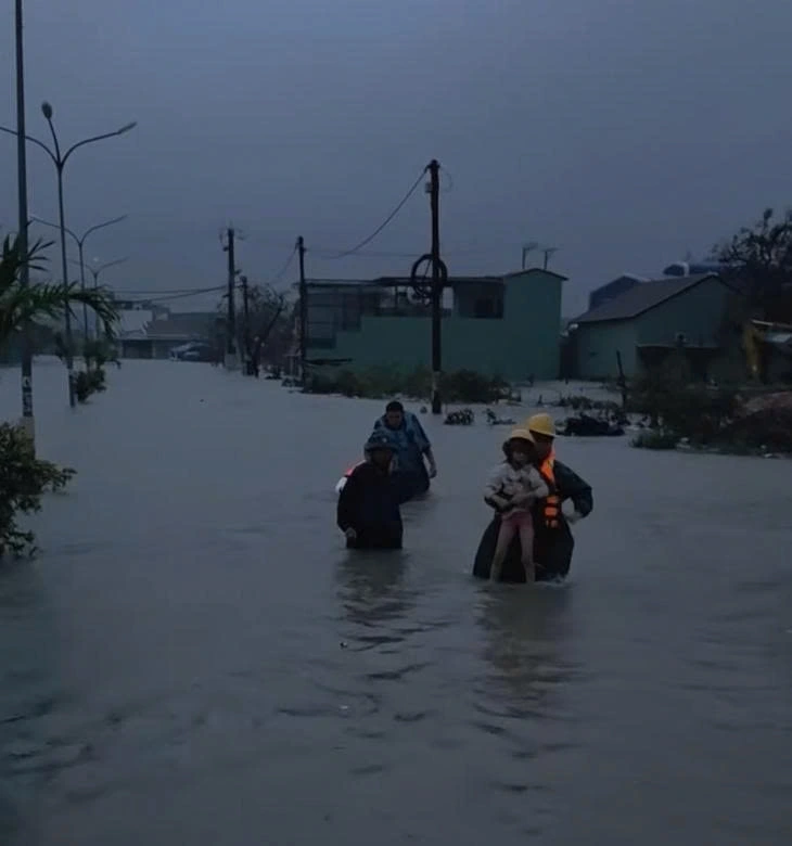 Công an phường Quy Nhơn Tây hỗ trợ người dân đi tránh lũ (Ảnh: Tuổi trẻ)