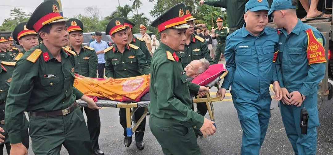 Các lực lượng kịp thời đưa cụ già qua khu vực nước sâu để chuyển lên xe đi cấp cứu