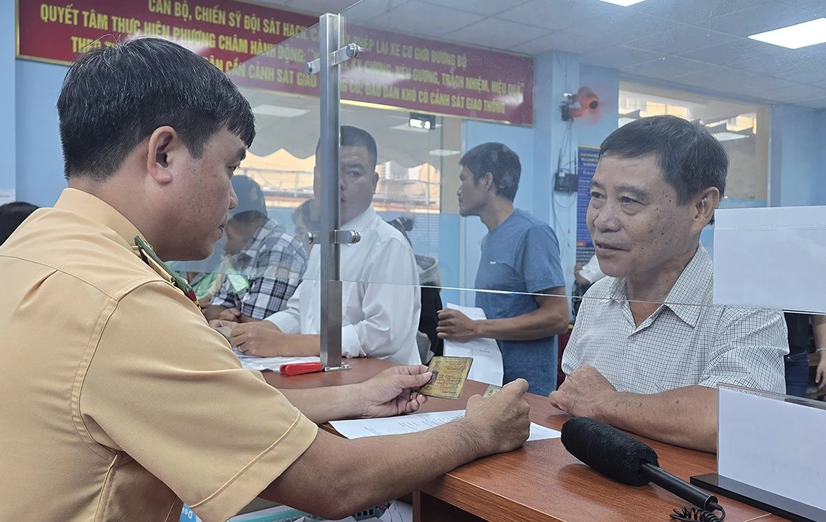 Cán bộ hướng dẫn người dân về những ưu điểm, thuận lợi của việc đổi GPLX từ thẻ bìa sang thẻ PET.