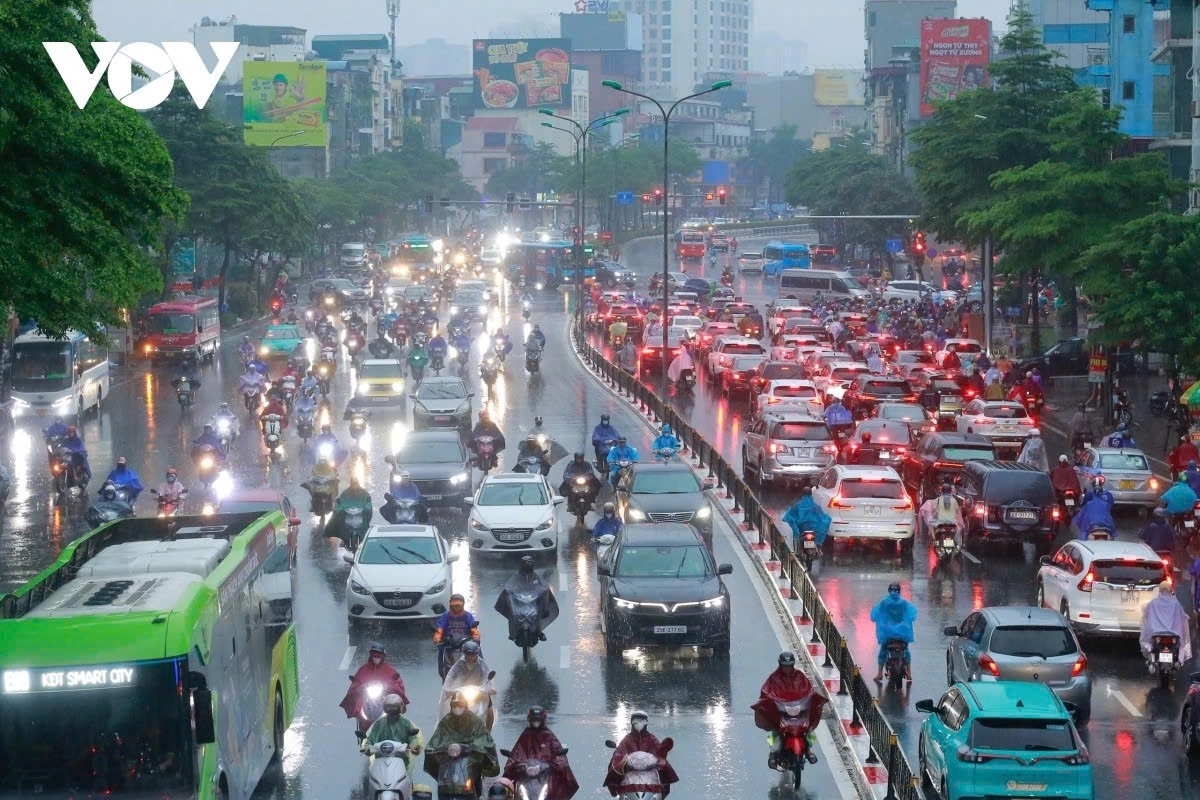 Mặc dù trời đã sáng, không gian vẫn phủ một lớp mưa mờ khiến tầm nhìn hạn chế. Trên đường, đèn xe vẫn đỏ rực, ô tô nối đuôi nhau, liên tục nháy đèn cảnh báo.