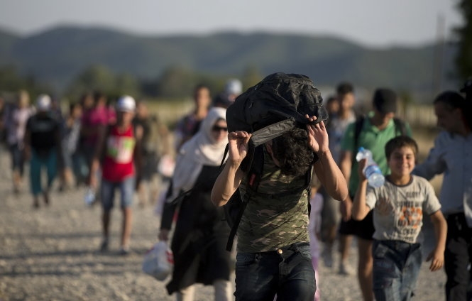 Người tị nạn dắt díu nhau vượt biên giới Macedonia - Hi Lạp. (Ảnh: Reuters)