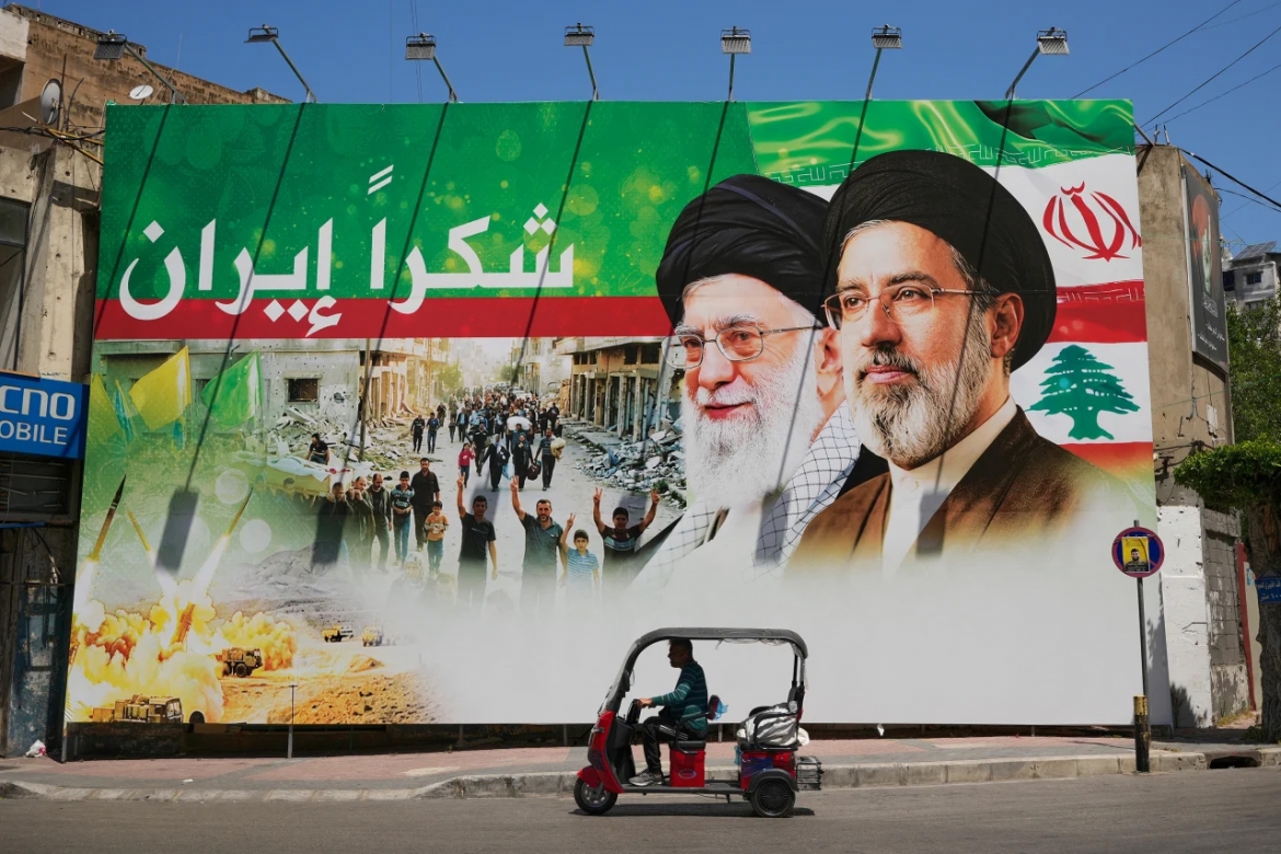 Một người đàn ông lái xe ba bánh chạy qua tấm biển có hình cố Lãnh tụ tối cao Iran Ali Khamenei và con trai ông, Mojtaba Khamenei, tại khu Dahiyeh, phía Nam thủ đô Beirut, Lebanon, ngày 15/6/2026. Ảnh: AP