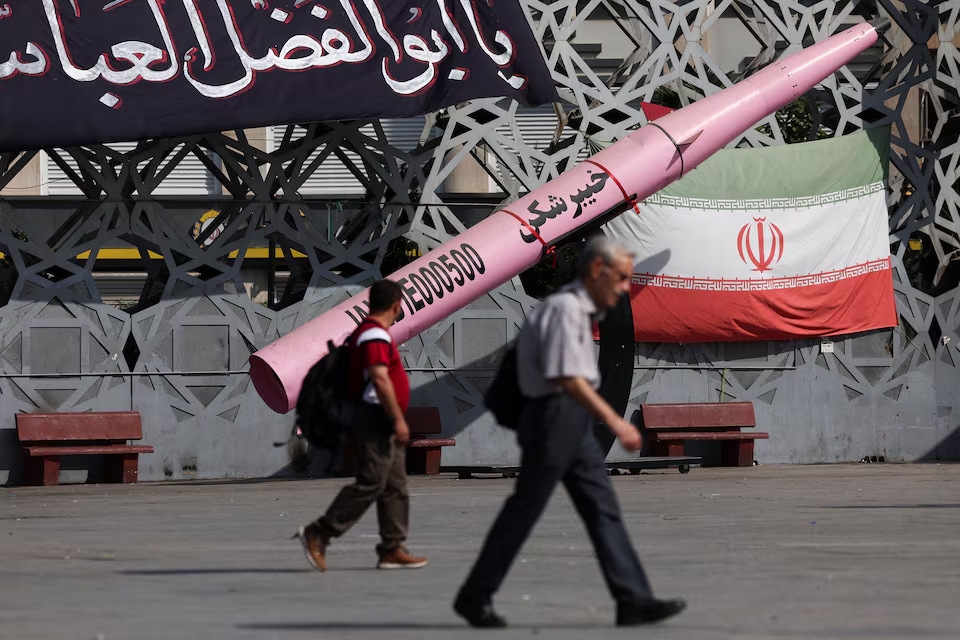 Người dân đi bộ bên cạnh mô hình tên lửa và quốc kỳ Iran tại Quảng trường Imam Hussein ở Tehran, Iran, ngày 12/7/2026. Ảnh: WANA/Reuters